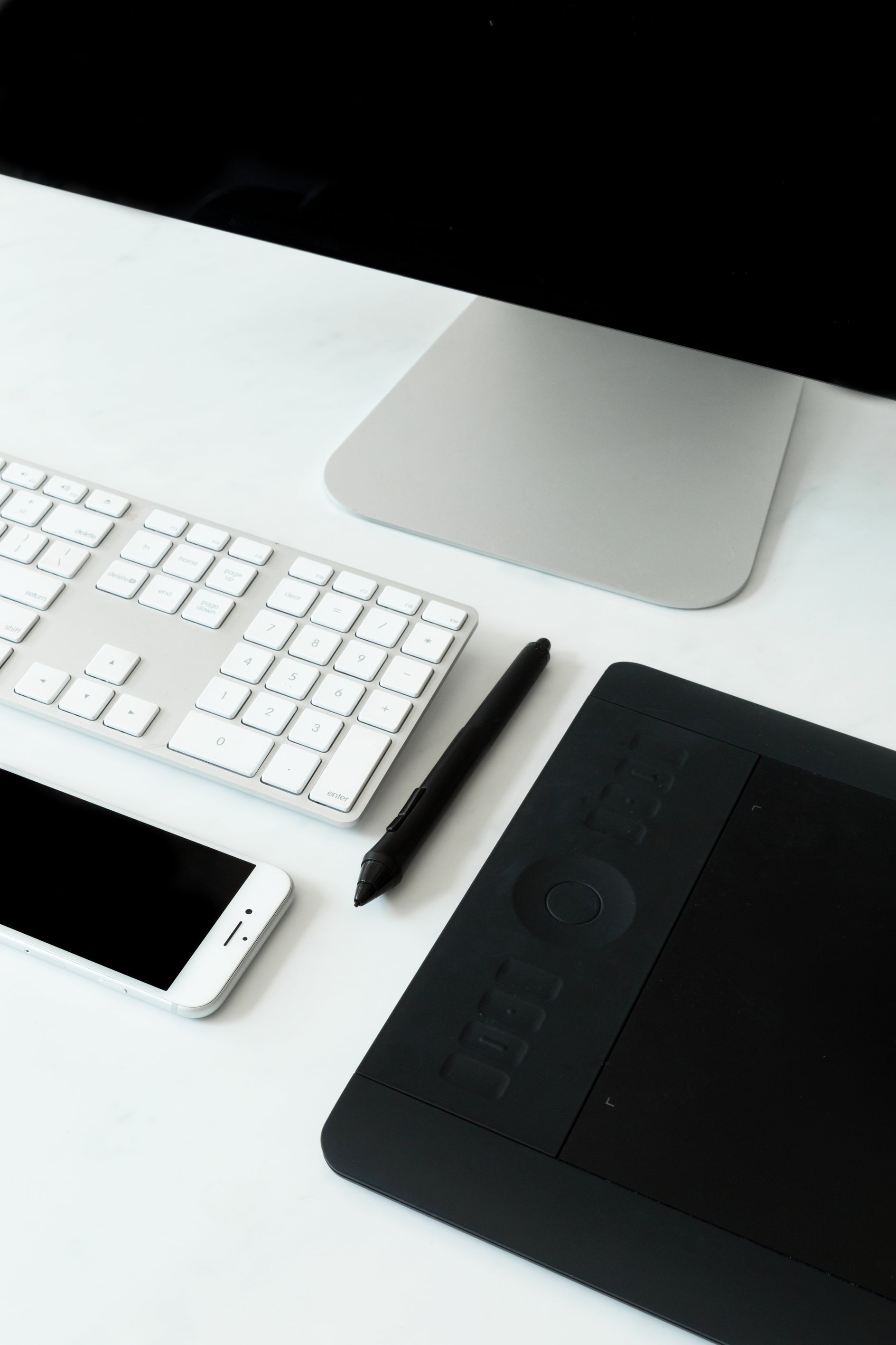 Minimal creative workspace with digital pen tablet, keyboard, smartphone and computer monitor for photo and video editing