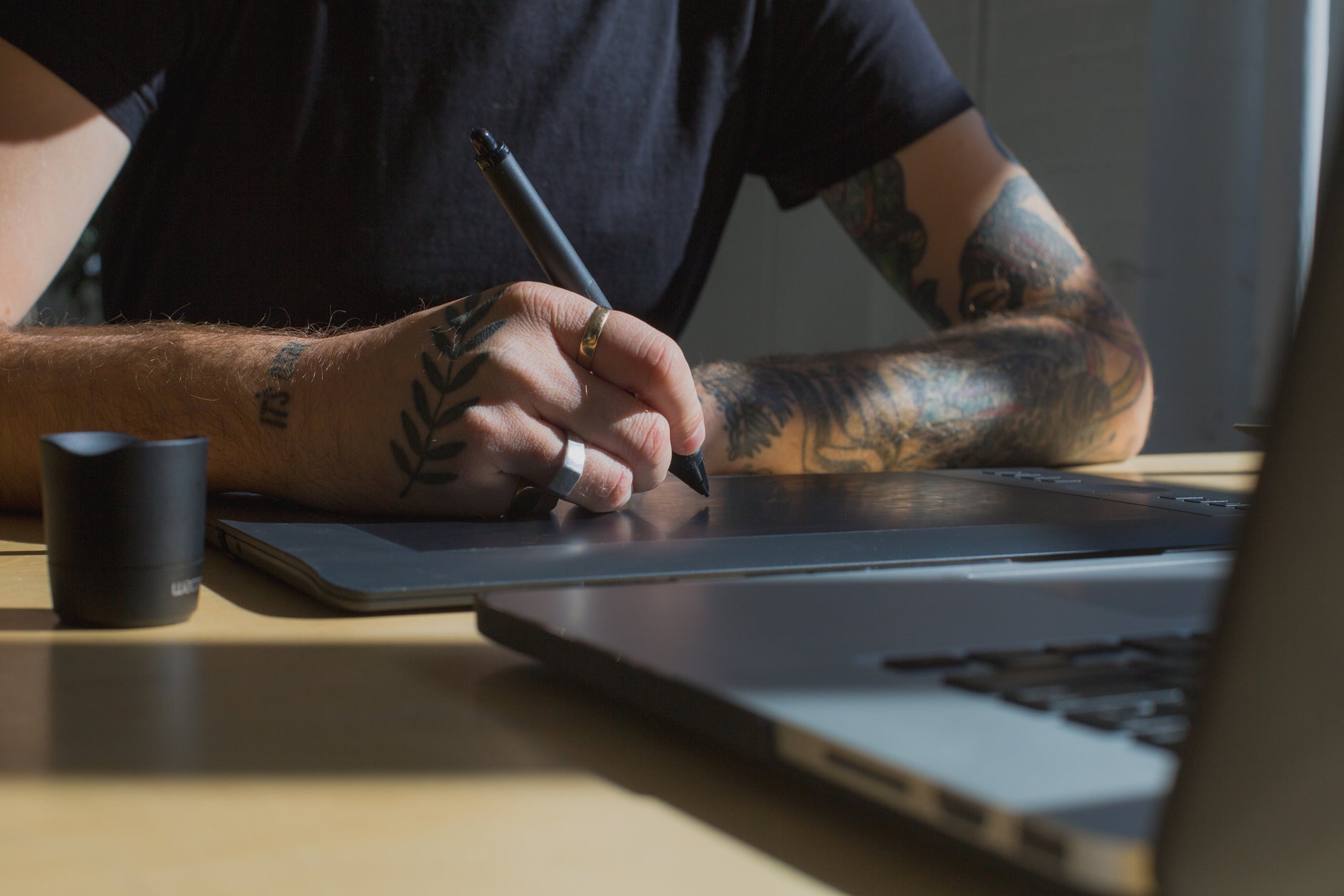 Creative designer working with a digital pen tablet and laptop in a photography and video editing studio